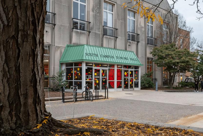 Exterior entrance of South Campus Dining Hall with a green awning and bicycle rack in front.